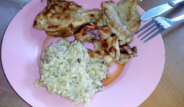 Вкусни пилешки пържолки на грил тиган и гарнитура кафяв ориз